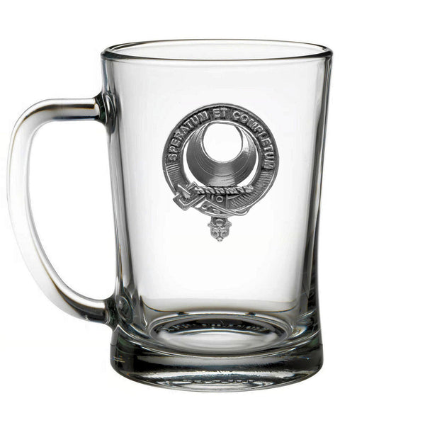 A clear glass mug with a metal emblem on it.