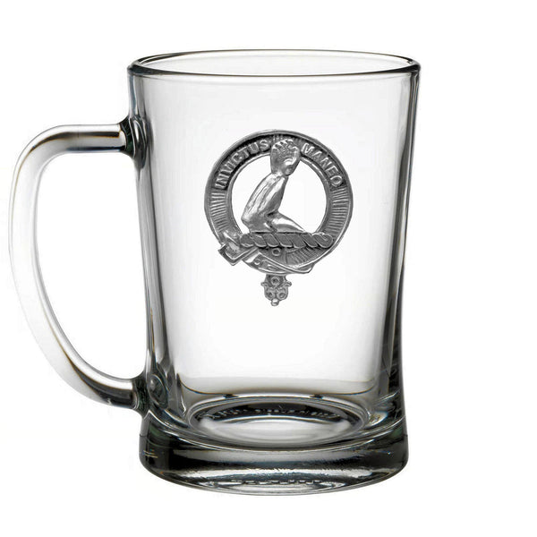A clear glass mug with a silver emblem on it.