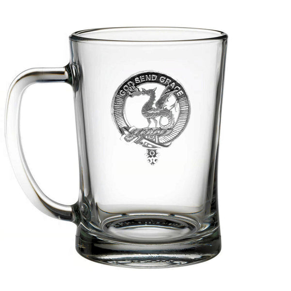 A clear glass mug with a metal emblem featuring a dragon and the text "GOOD SEND GRACE" printed on it.