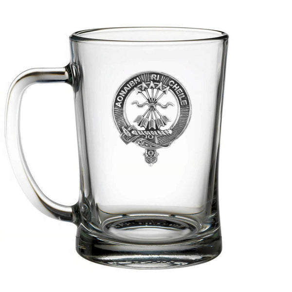 A clear glass mug with a metal emblem on it.