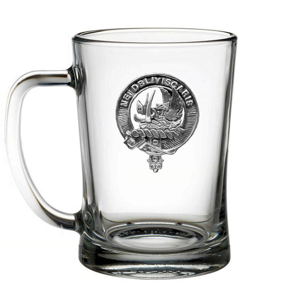A clear glass mug with an embossed emblem on it.