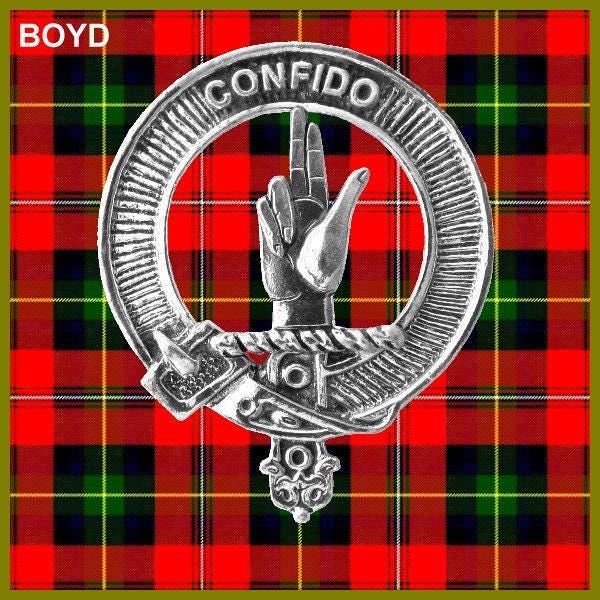 a metal emblem with a hand gesture, set against a background of red and green plaid fabric.