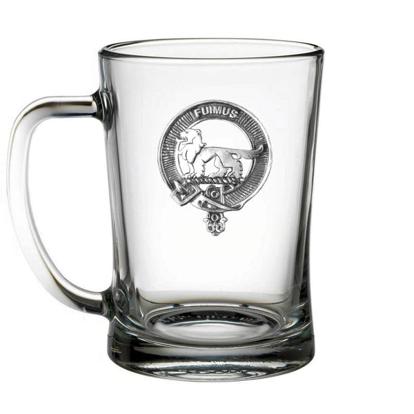 A clear glass mug with a silver emblem on it.