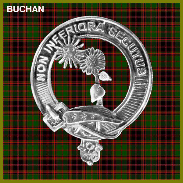 a silver badge with a circular design, including a sun, flower, and leaf motif, set against a red and green plaid background.