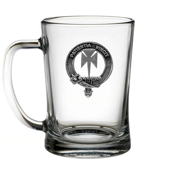 A clear glass mug with a metal emblem on it.