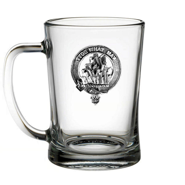 A clear glass mug with a metal emblem on it.