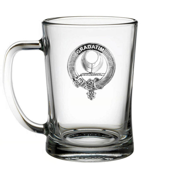 A clear glass mug with a metal emblem featuring a shield and a crescent moon.