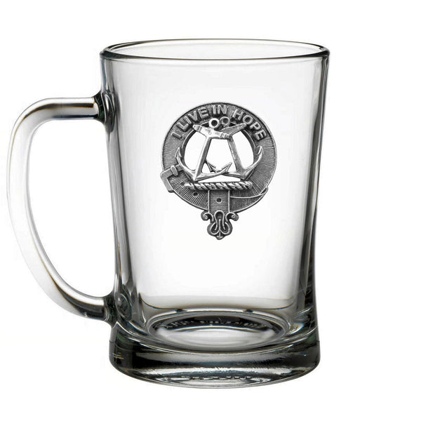 A clear glass mug with an embossed metal emblem on it.