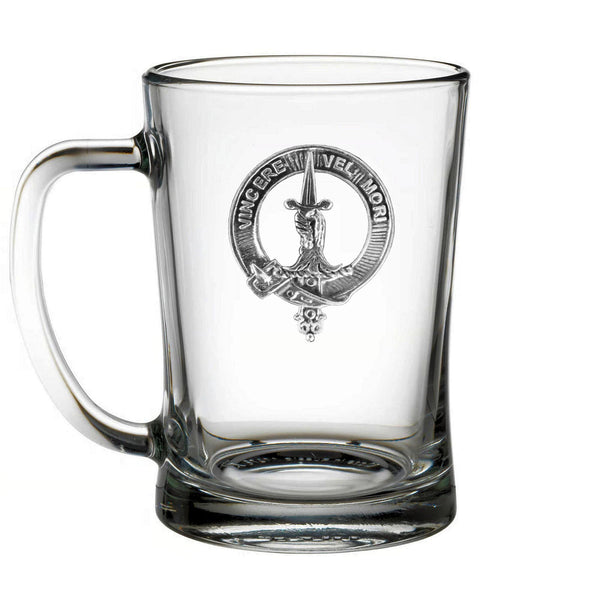 A clear glass mug with a silver emblem on it.