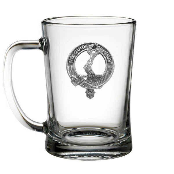 A clear glass mug with a silver emblem on it.