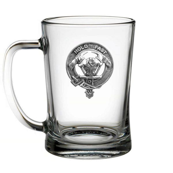 A clear glass mug with a metal emblem on it.