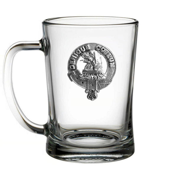 A clear glass mug with an embossed metal emblem on it.