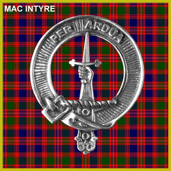 a silver metal emblem with a sword and a crown, set against a background of red and green plaid fabric.