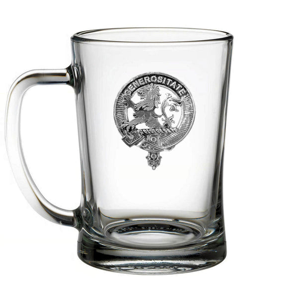 A clear glass mug with a metal emblem on it.