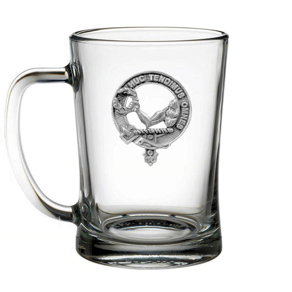 A clear glass mug with a metal emblem on it.