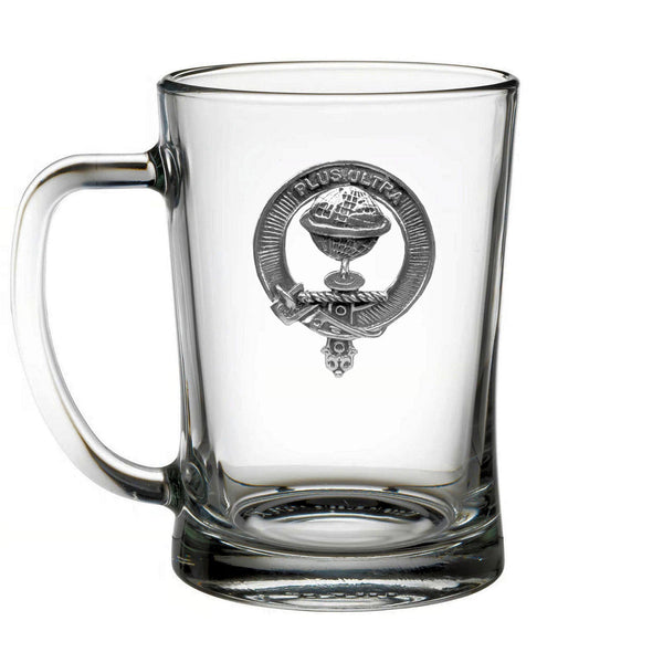 A clear glass mug with a metal emblem on it.