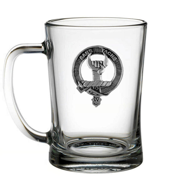 A clear glass mug with a metal emblem on it.