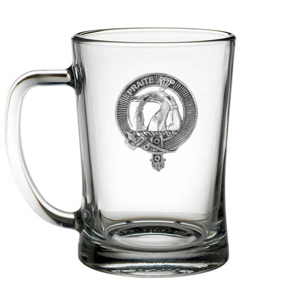 A clear glass mug with a silver emblem on it.