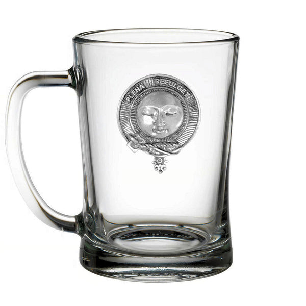 A clear glass mug with a silver emblem on it.