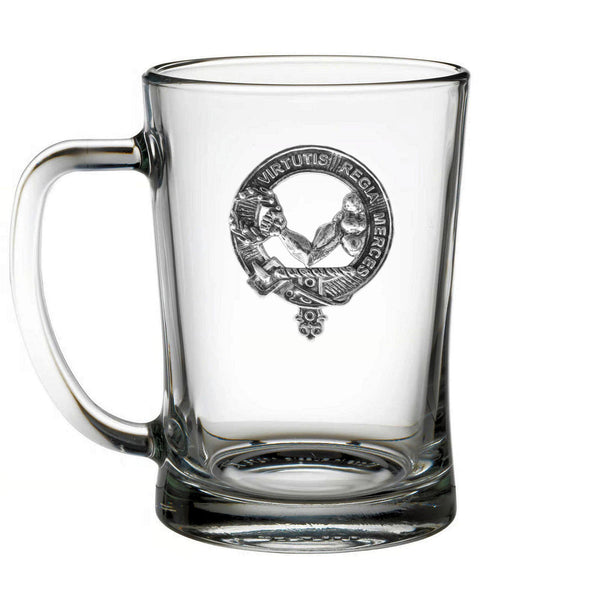 A clear glass mug with a metal emblem on it.