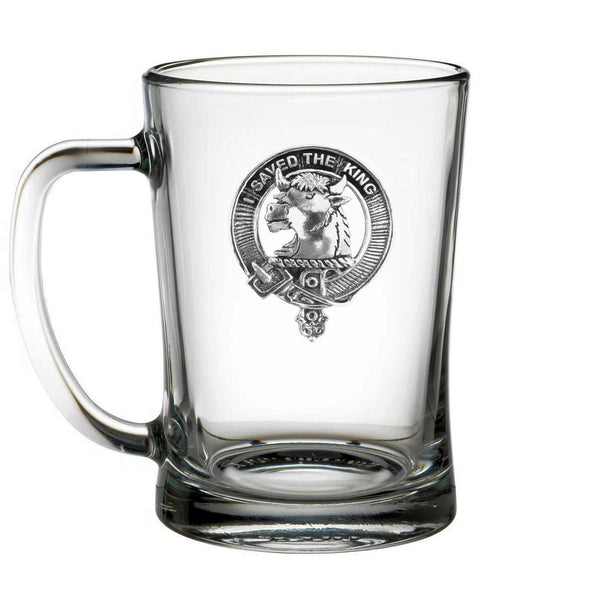 A clear glass mug with a silver emblem on it.