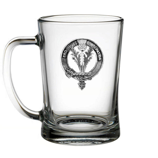 A clear glass mug with a metal emblem on it.