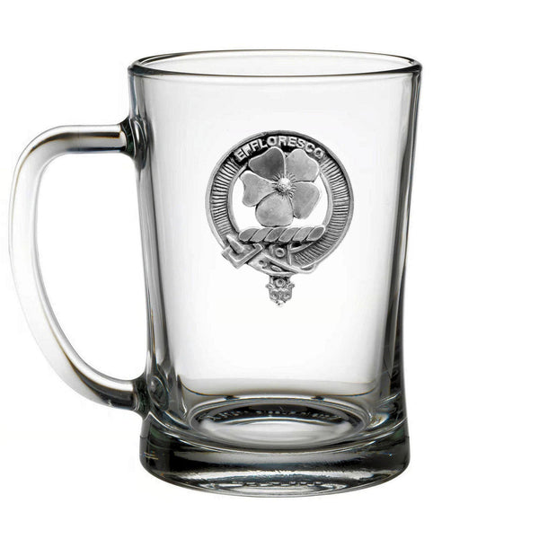 A clear glass mug with a silver emblem on it.