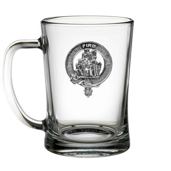 A clear glass mug with a silver emblem on it.