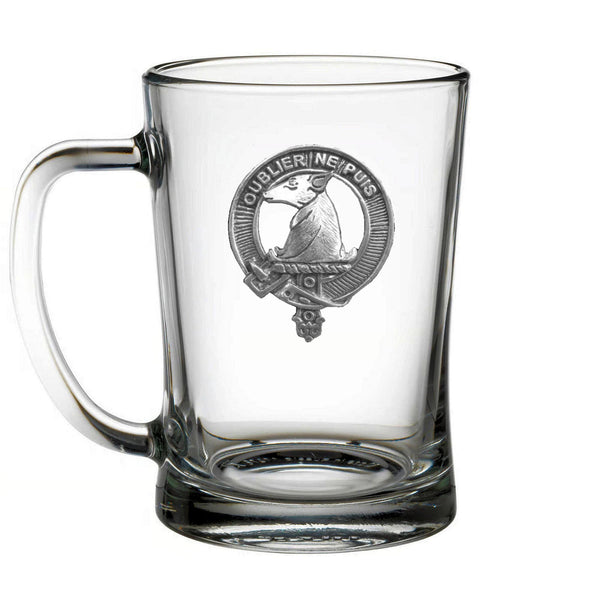 A clear glass mug with an embossed metal emblem on it.