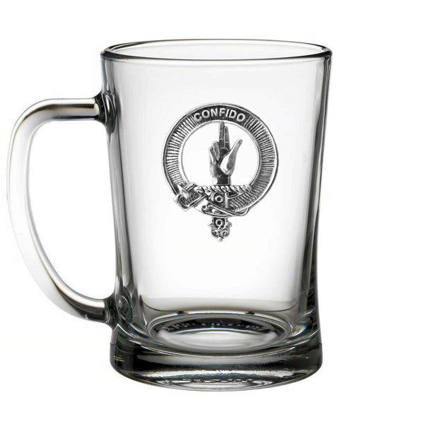 A clear glass mug with a metal emblem on it.
