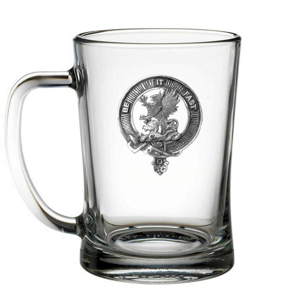 A clear glass mug with a metal emblem on it.