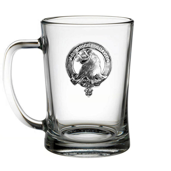 A clear glass mug with a silver emblem on it.