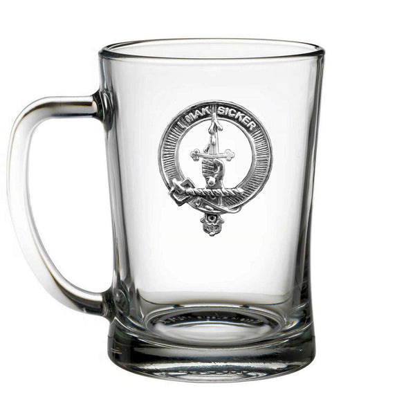 A clear glass mug with a silver emblem on it.
