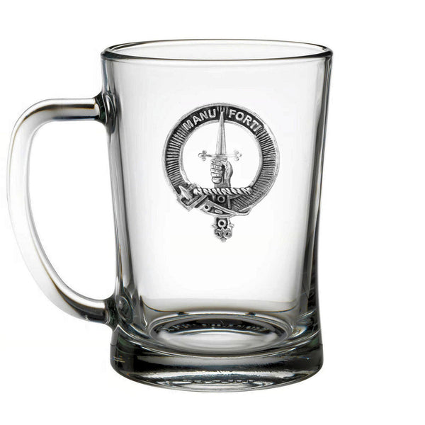 A clear glass mug with a metal emblem featuring a sword and the words "MANU FORT" printed on it.