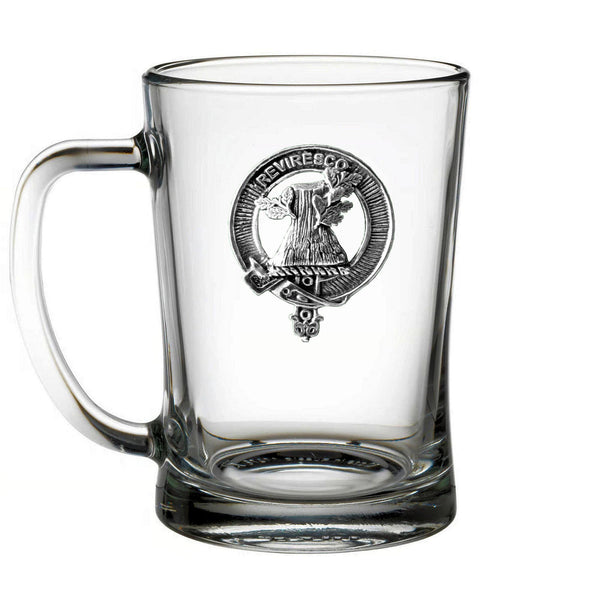 A clear glass mug with a metal emblem on it.