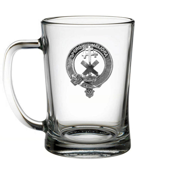 A clear glass mug with a silver emblem on it.