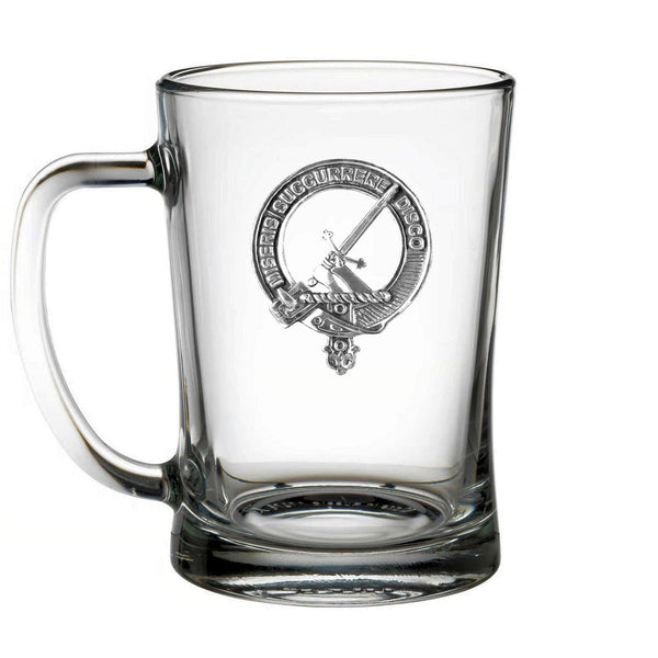A clear glass mug with a silver emblem on it.