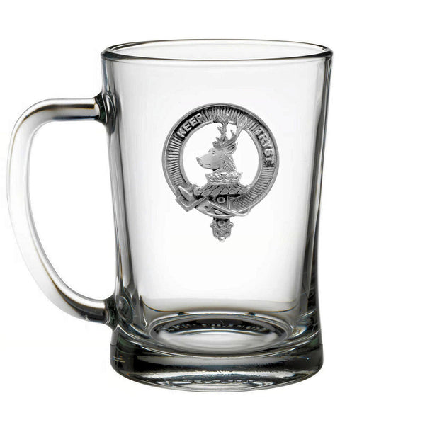 A clear glass mug with a silver emblem on it.