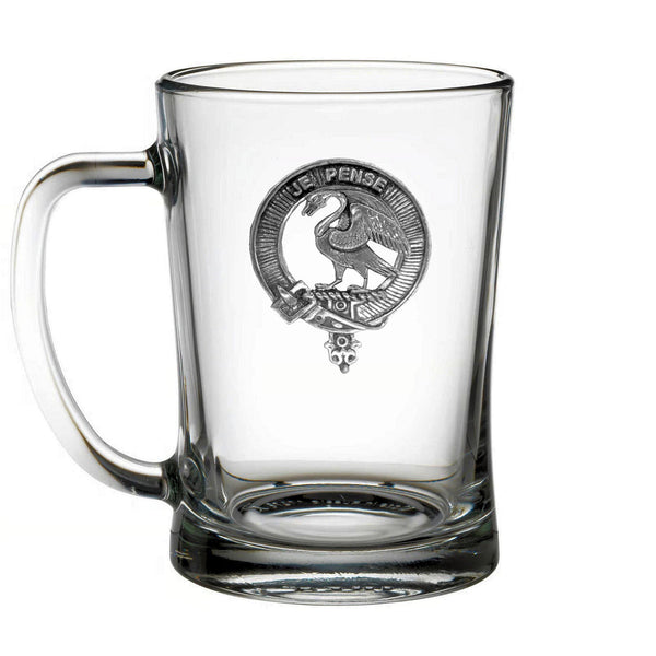 A clear glass mug with a metal emblem on it.